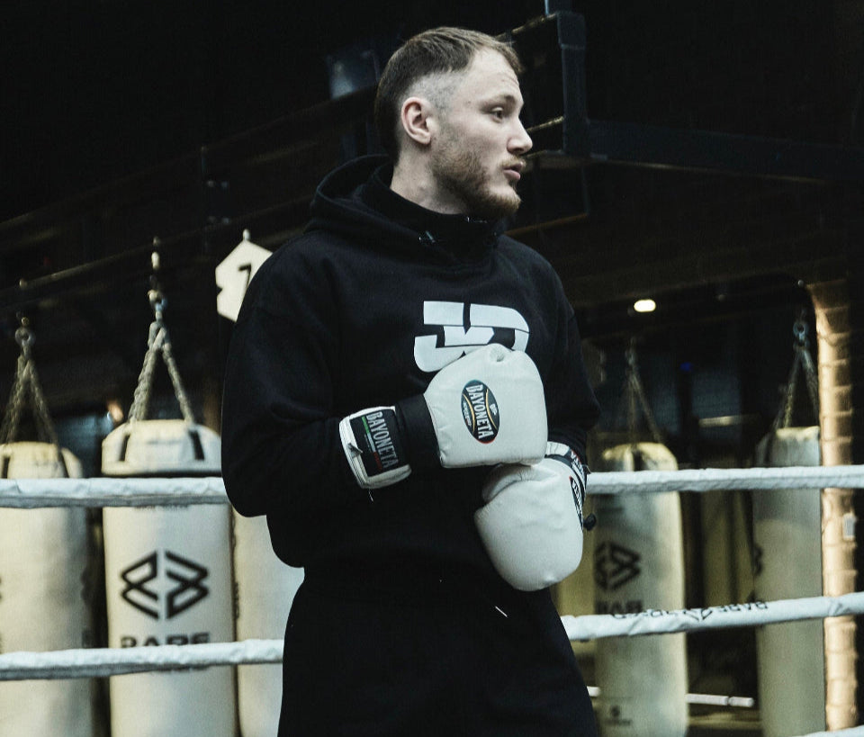 Person in a boxing ring wearing outfit with visible branding.